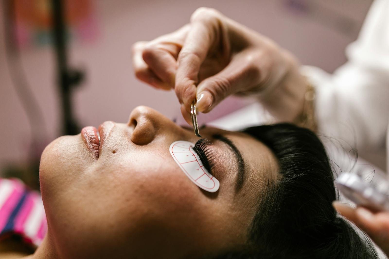 Close-up of a woman receiving eyelash extensions at a beauty salon.